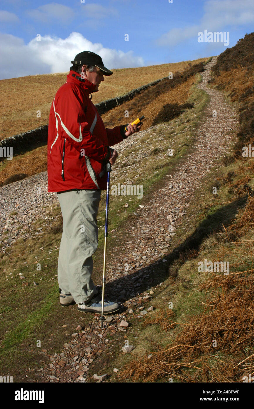 Walker using a GPS handheld navigation system on a hike in the Pentland