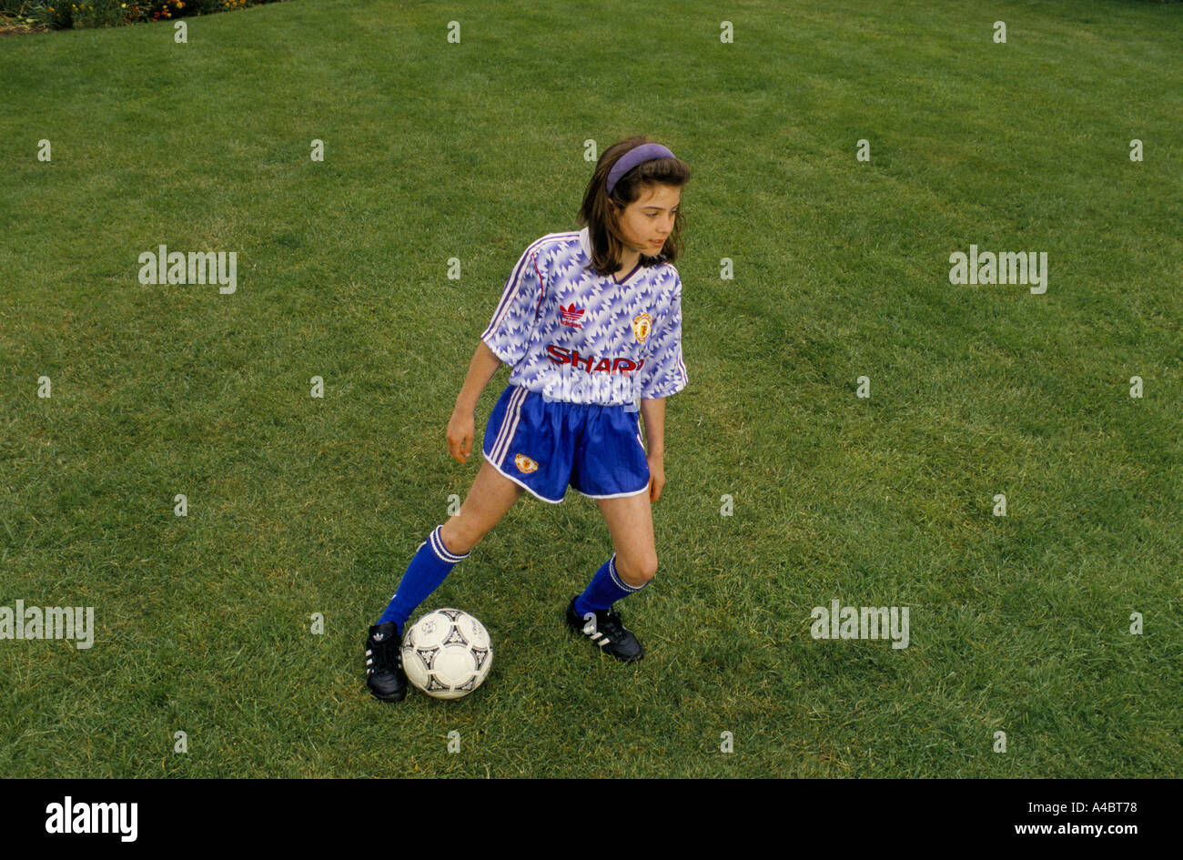 A young girl plays football in a london park while being coached Stock