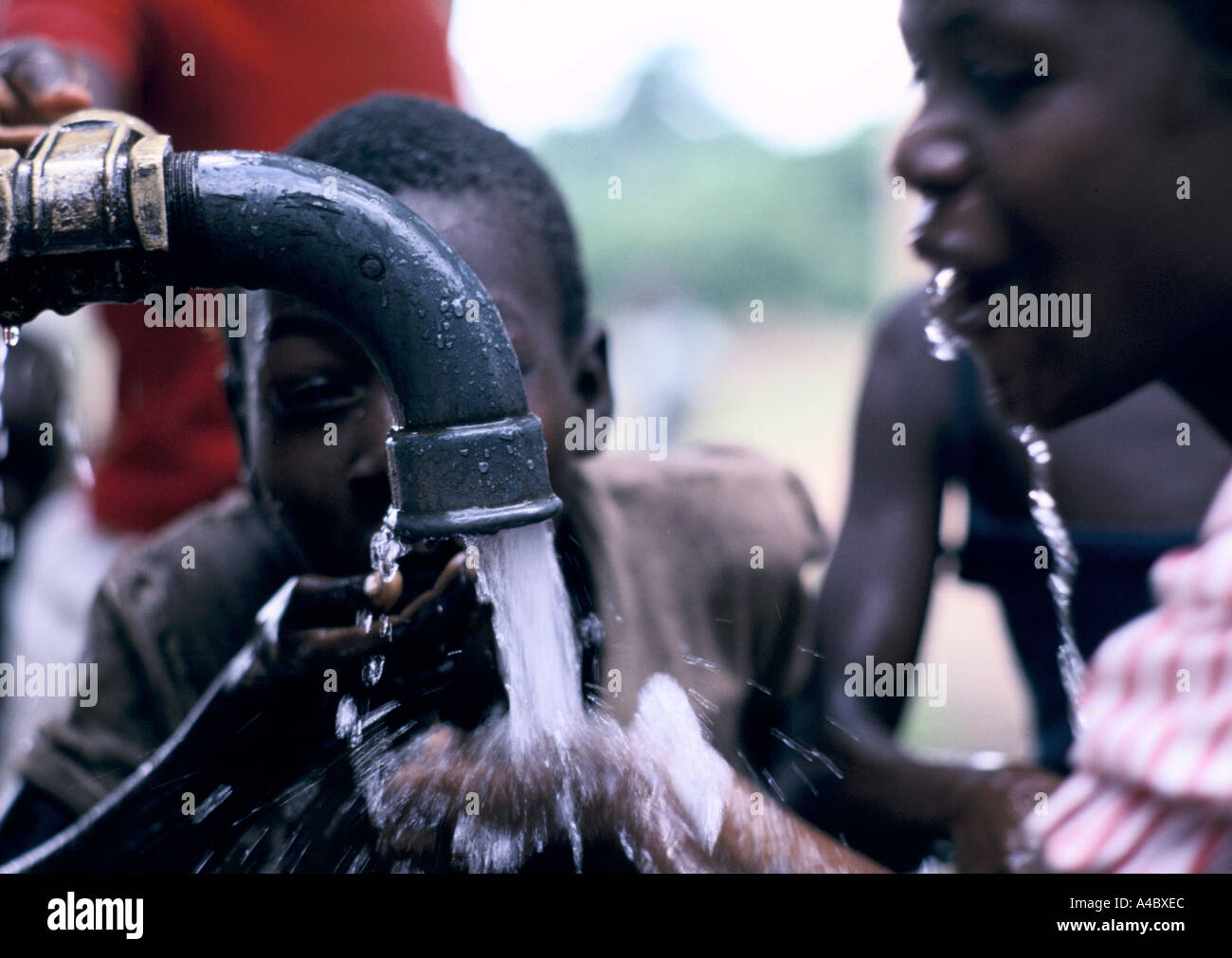 Maputo, Mozambique: Children drinking water from a pump in the  green zones agricultural project Stock Photo