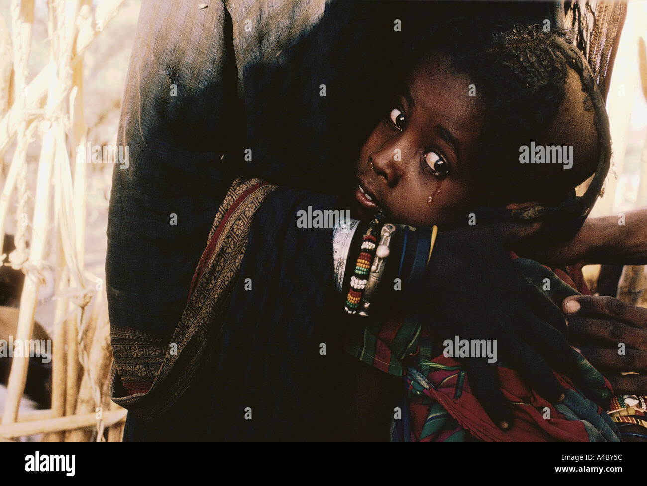 CRYING CHILD, BEING HELD IN MOTHERS ARMS, ERITREA, ETHIOPIA, 1991 Stock Photo