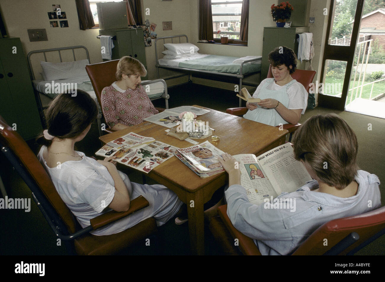 Four pregnant inmates sit around a table reading baby magazines.' Stock Photo