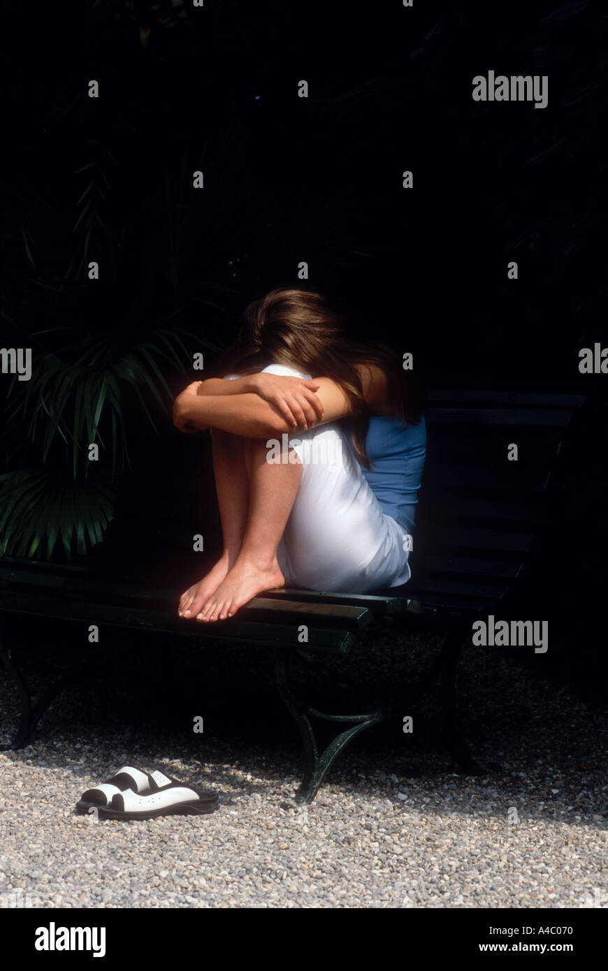 Depressed or resting girl on garden bench Stock Photo
