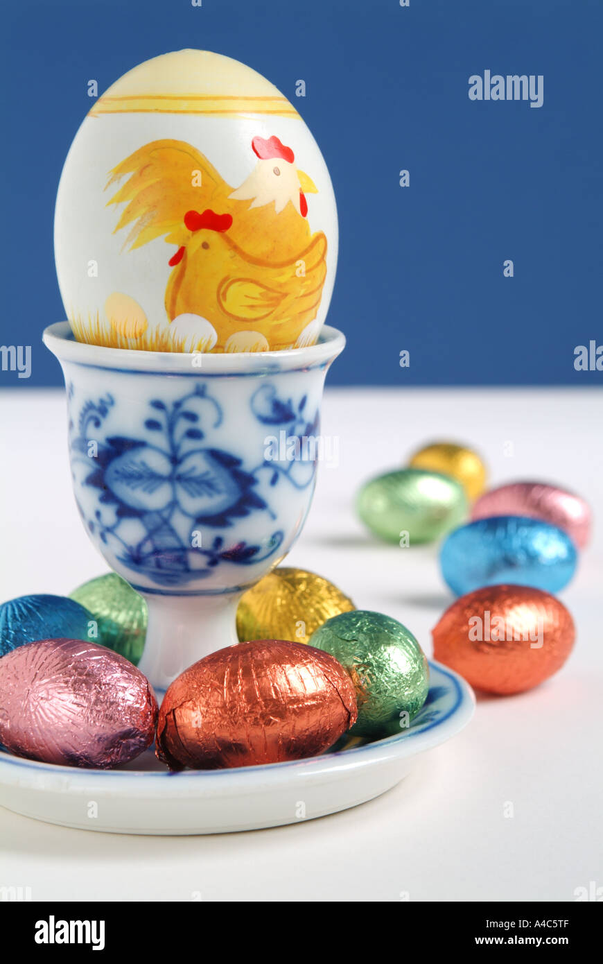 Painted and chocolate Easter eggs in and around a blue and white egg cup Stock Photo