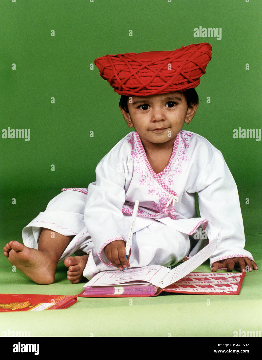 A little boy dressed in traditional Indian attire and wearing a turban ...