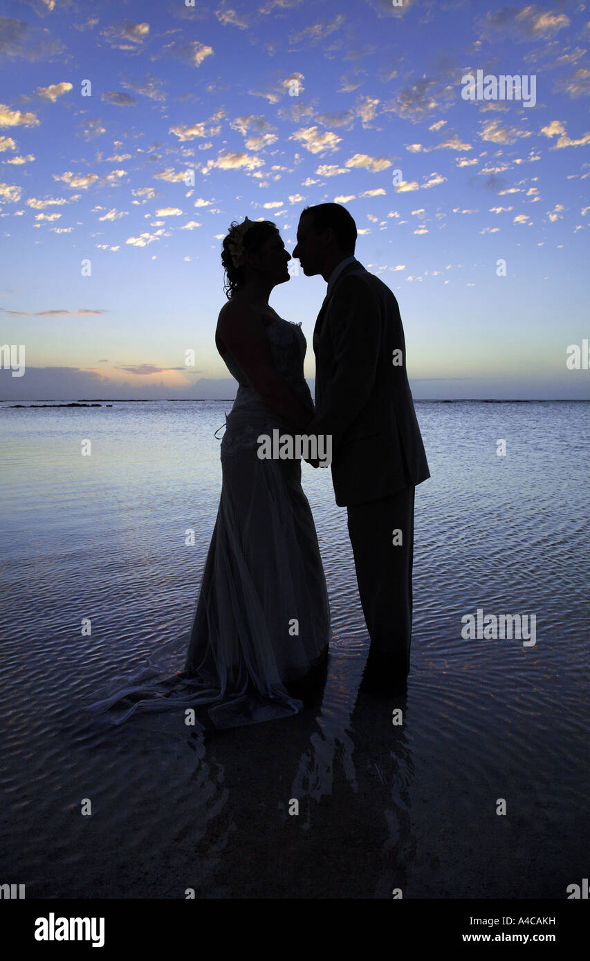 romantic couple silhouetted by the sunset and standing in water Stock Photo