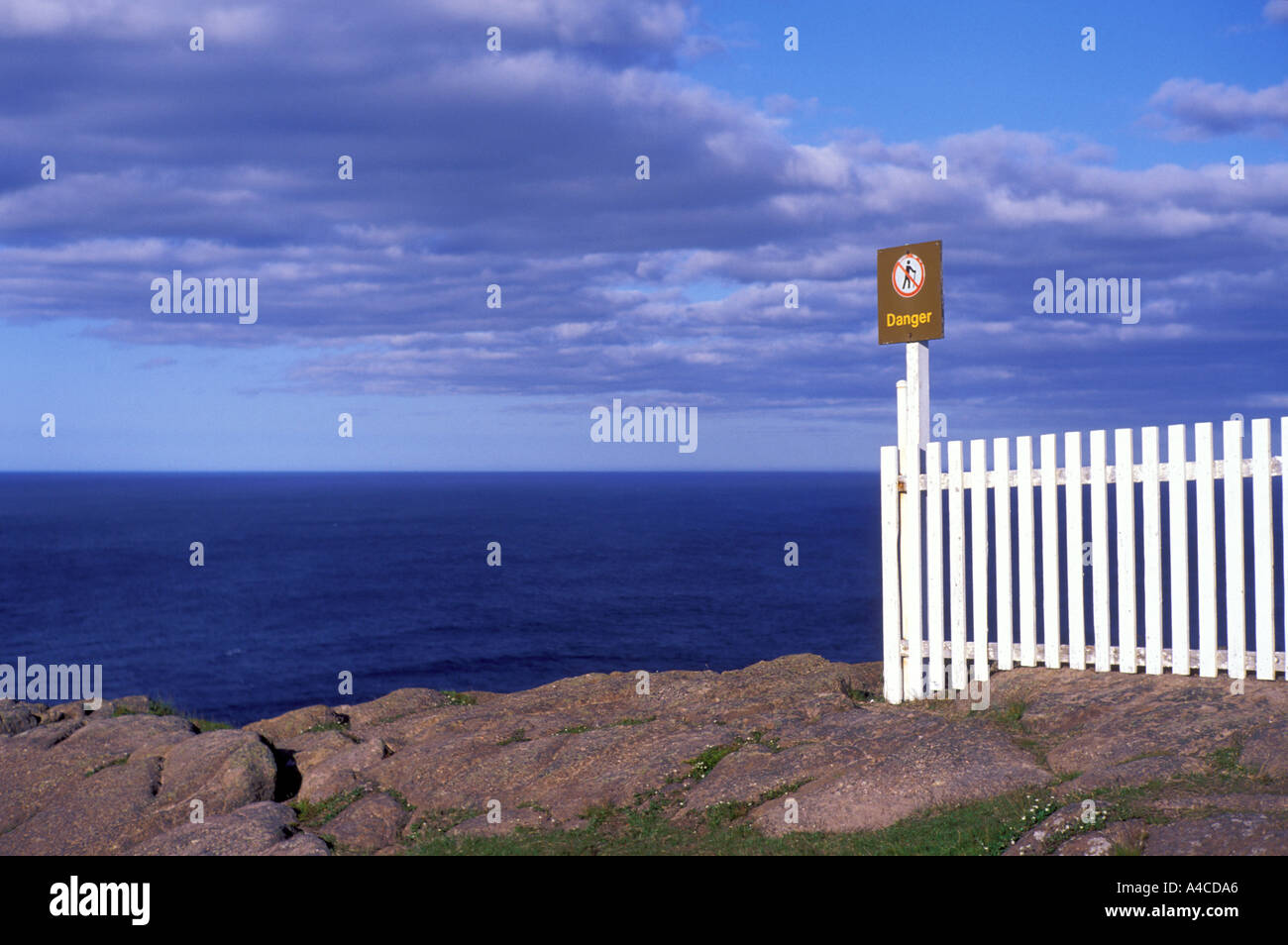 Danger sign and white fence along cliff in Newfoundland Canada Stock Photo