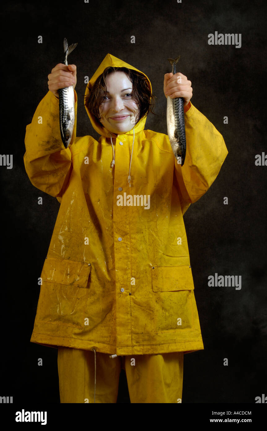 A woman in yellow oilskins holding raw fish Stock Photo Alamy