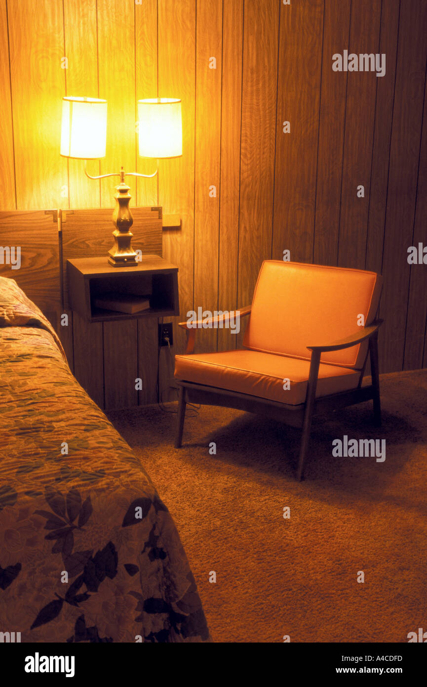 Evening motel room scene showing bed nightstand and chair Stock Photo