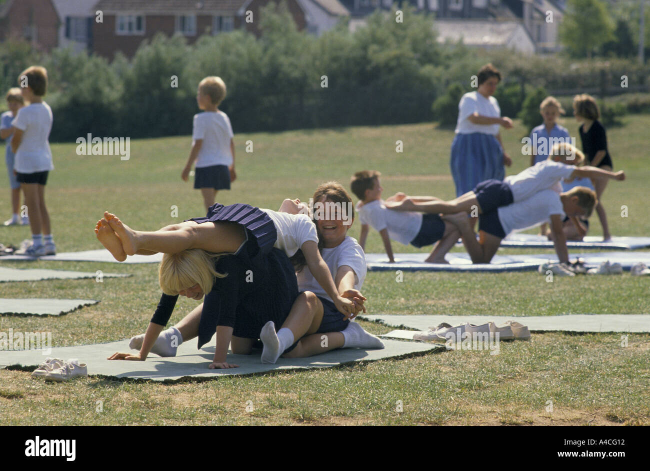 PUPILS DOING EXERCISE ON MAT DURING PHYSICAL EDUCATION LESSON IN PRIMARY SCHOOL Stock Photo