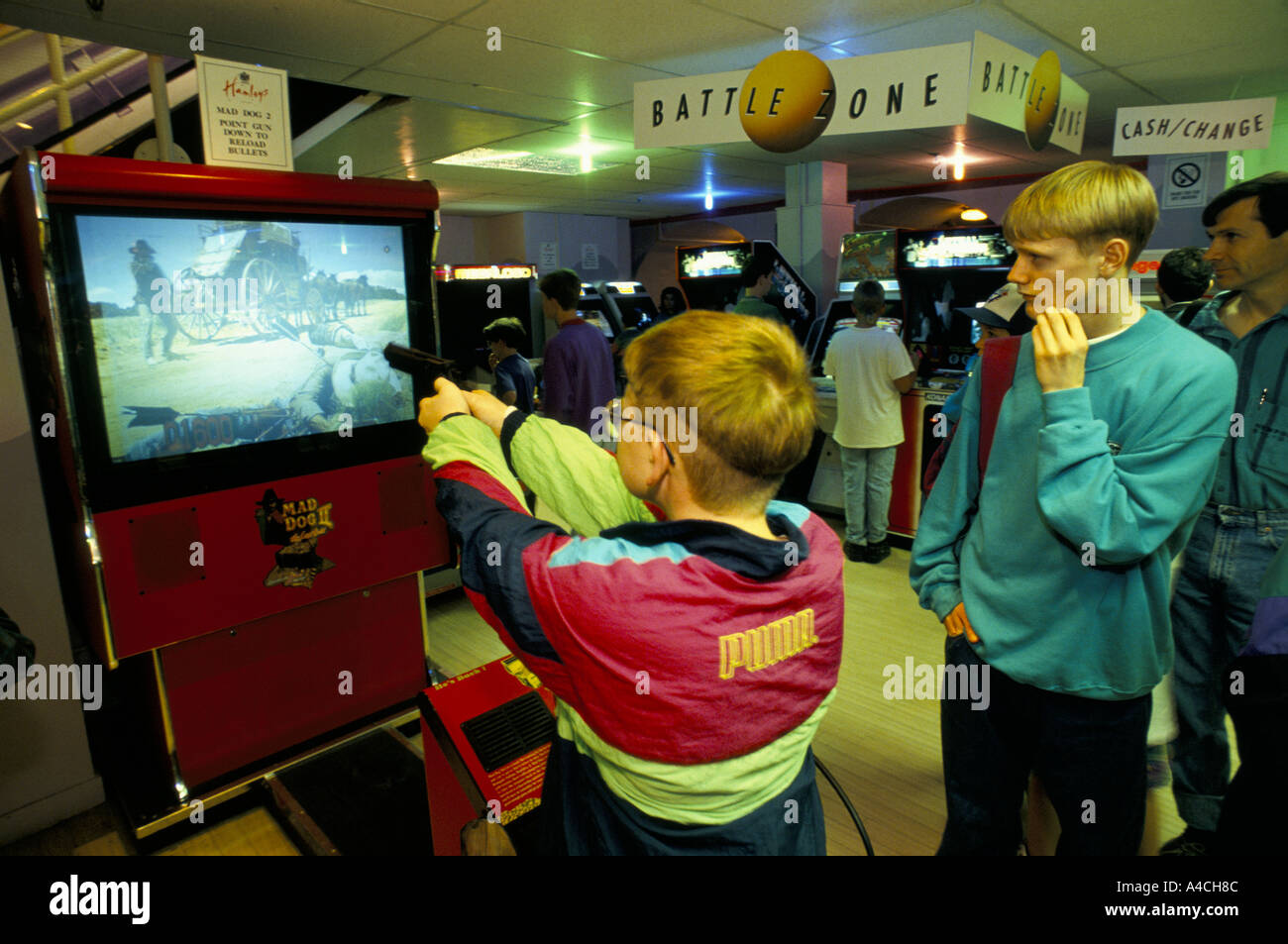 A teenage boy plays Mad Dogs 2, a virtual reality interactive shooting game at Hamleys toy shop, London England 08 93 Stock Photo