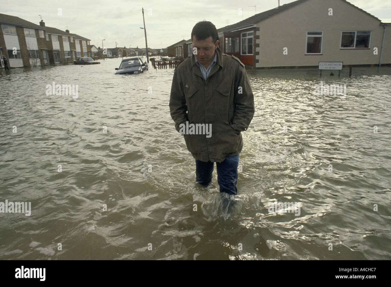 Wading through his flooded street after Hurricane winds cause the sea wall at Towyn, North Wales to be break flooding the town, Feb 1990. Stock Photo