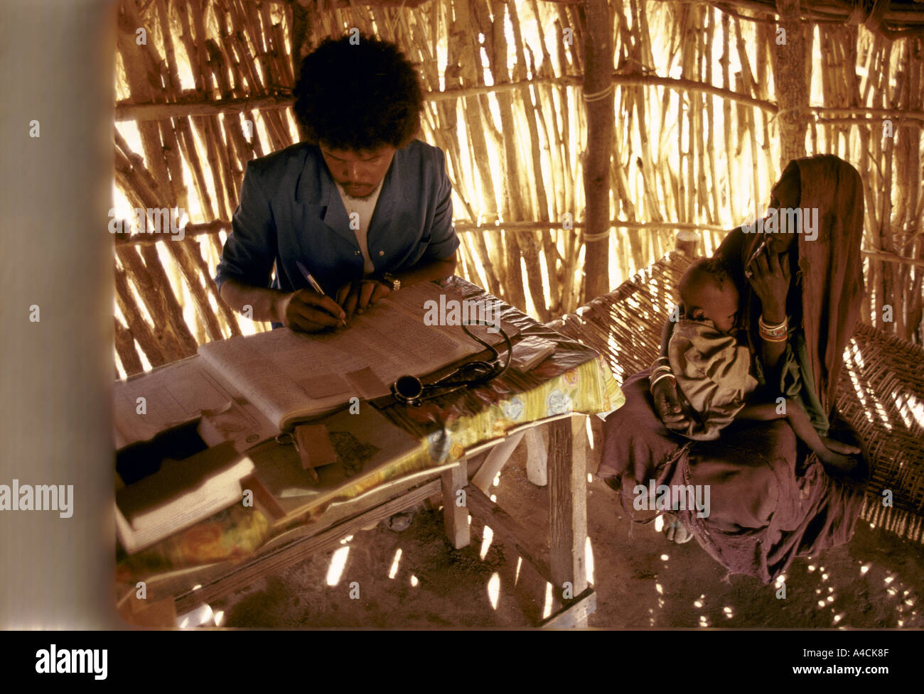 medical worker doctor nurse making notes woman child baby at e r a health clinic barka province eritrea nov 1990 Stock Photo