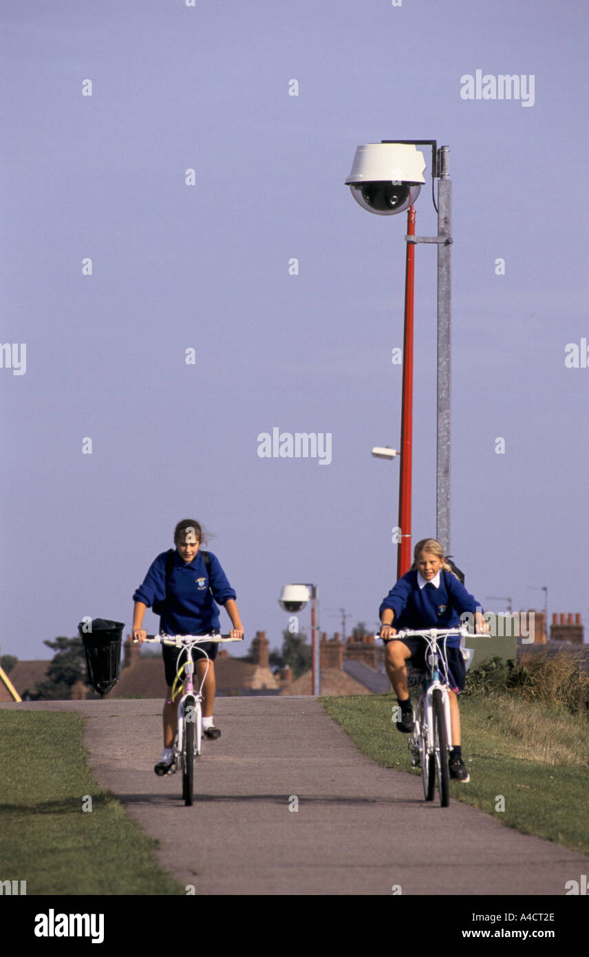 Girls cycle home from school through a park, watched over by