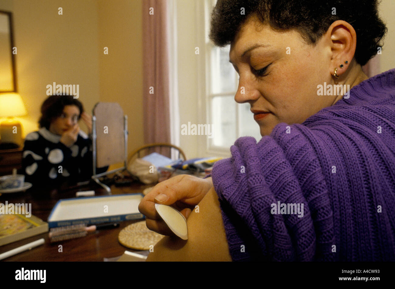 "SMOKESTOP' LUNDY ISLAND 1994, A MOTHER PUTTING ON HER SKIN PATCH WHILE HER DAUGHTER, PUTS ON HER MAKE-UP Stock Photo