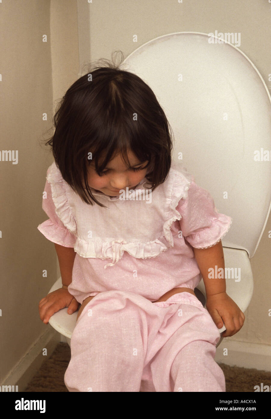 Little girl sitting on the toilet Stock Photo