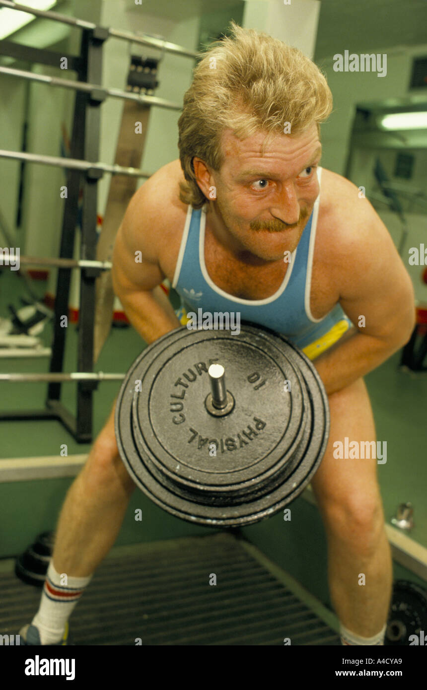 Strain showing on the sweating red face of man weight training in a gym, UK Stock Photo