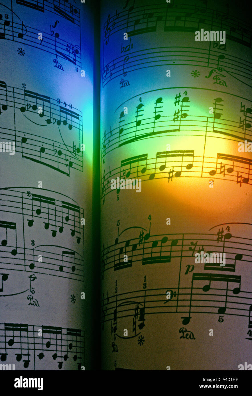 A rainbow of colours cast by a prism, illuminates a page of piano music by Chopin. Stock Photo
