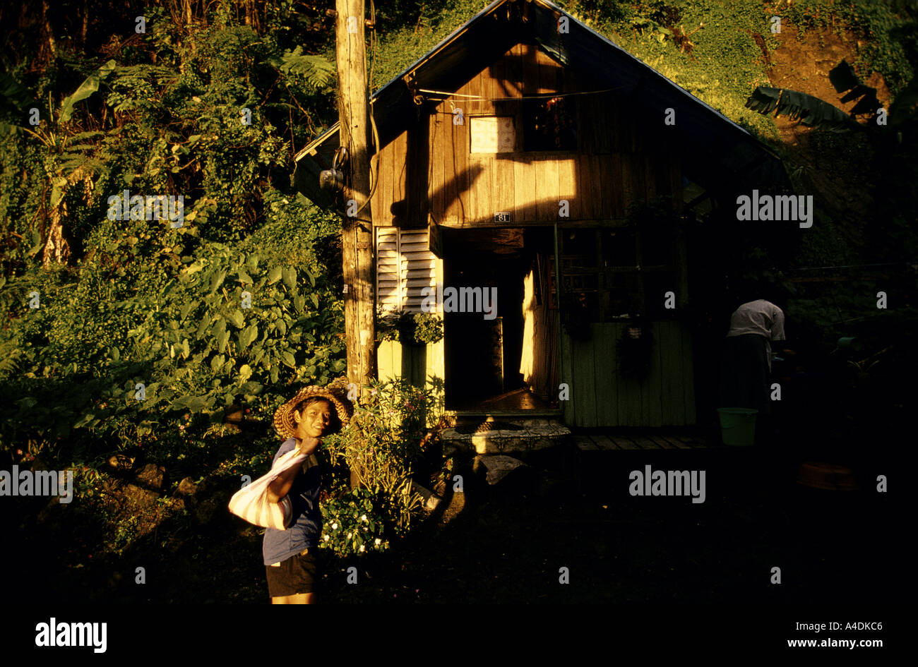 A young person in straw hat in front of a small wooden house, Mount Diwata, Mindanao, The Philippines Stock Photo