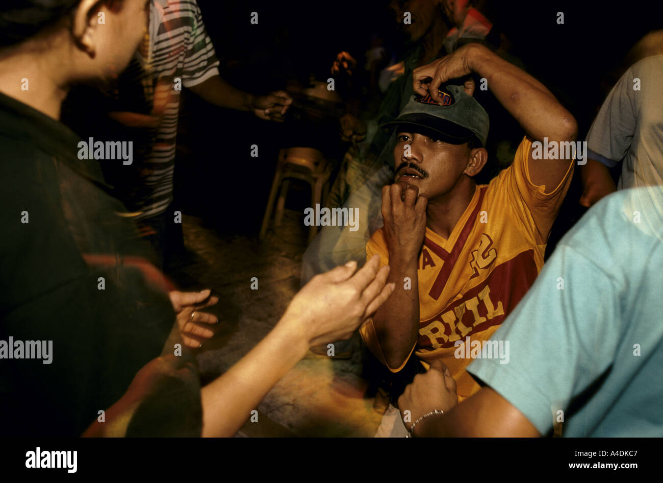 A man in a baseball cap scratches his head and chin in a bar Mount Diwata, Mindanao, The Philippines Stock Photo