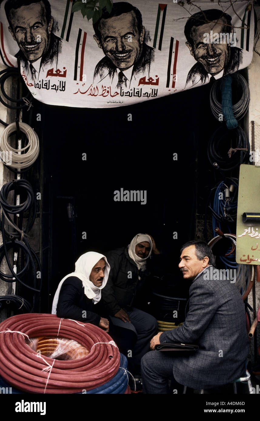 Group of men sitting under posters of President Assad in the central  market. Damascus, Syria. Stock Photo