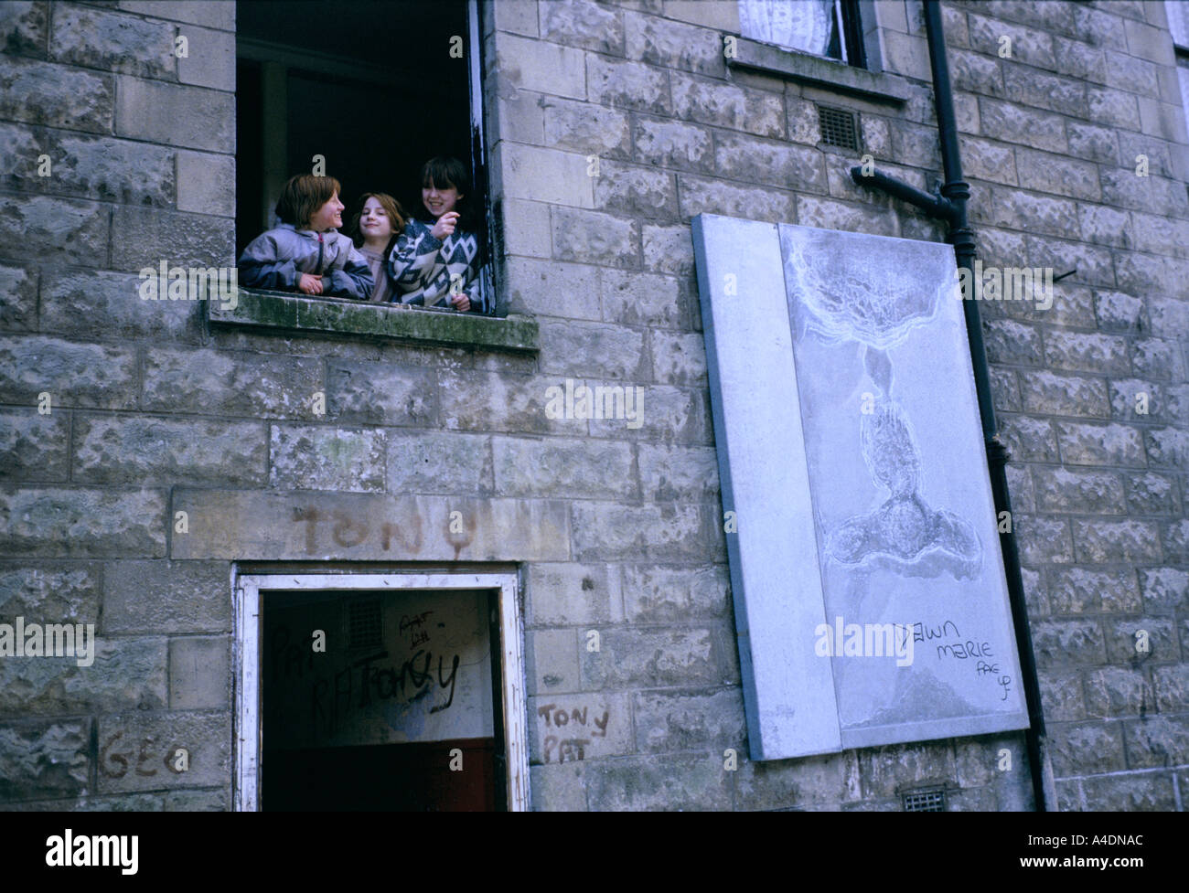Three children at an open window on the Possil Estate, Glasgow, Scotland Stock Photo