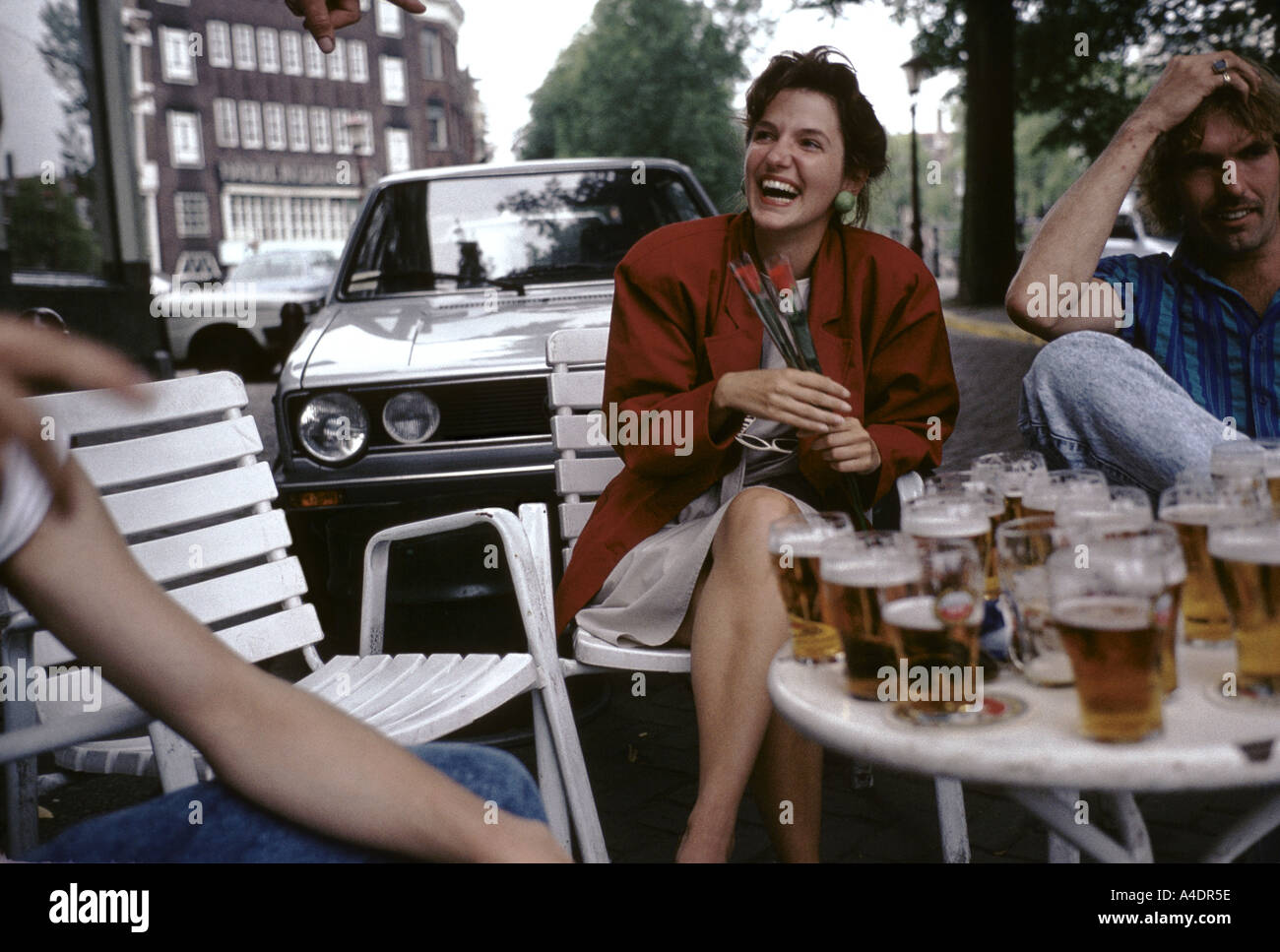 A woman with two red roses in her hands having a laugh at a cafe terrace, Holland Stock Photo