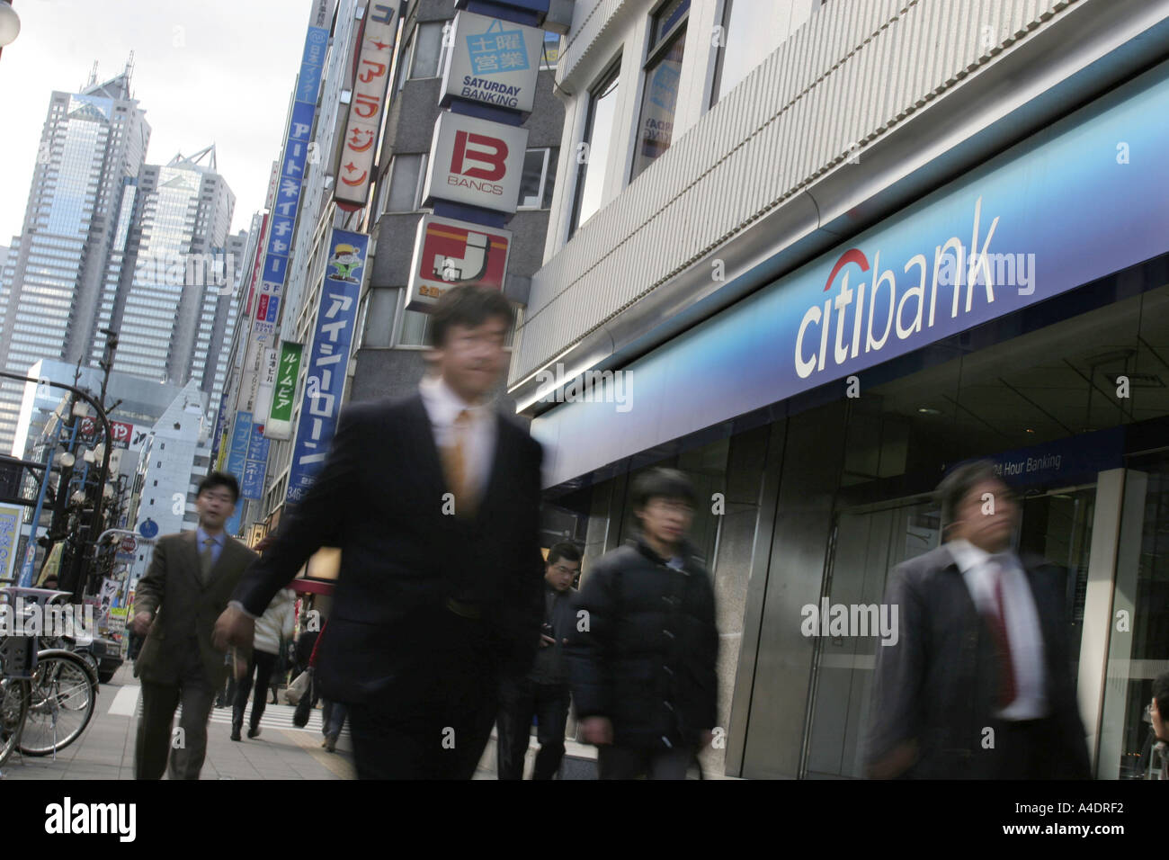 business men walk past Citibank Japan branch in the Shinjuku district of Tokyo, Japan. Stock Photo