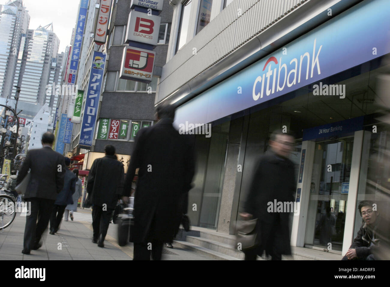 business men walk past Citibank Japan branch in the Shinjuku district