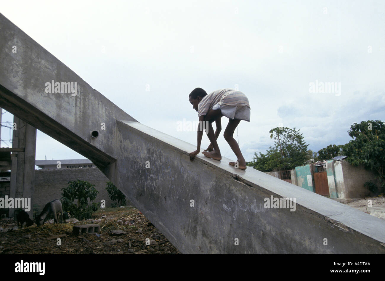 A boy climbing a concrete rampart in Haiti Stock Photo