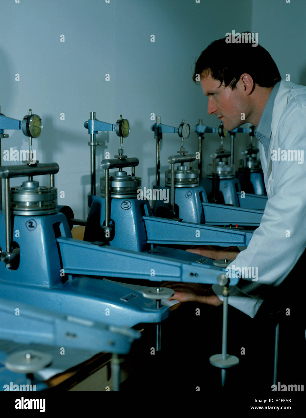 Technician reading strain gauges on soil consolidation test apparatus