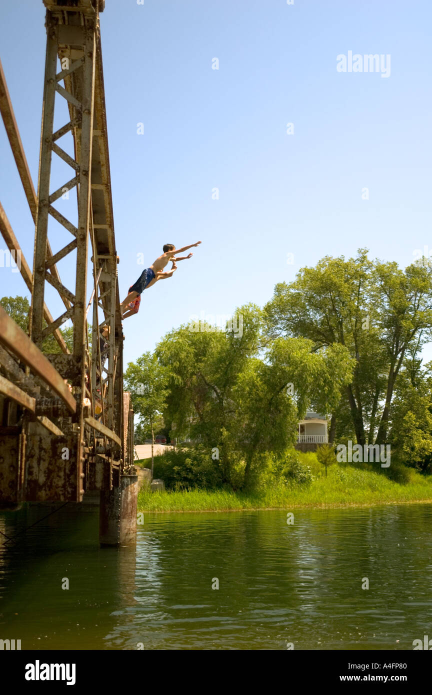 Three boys jumping off of bridge into a river Stock Photo - Alamy