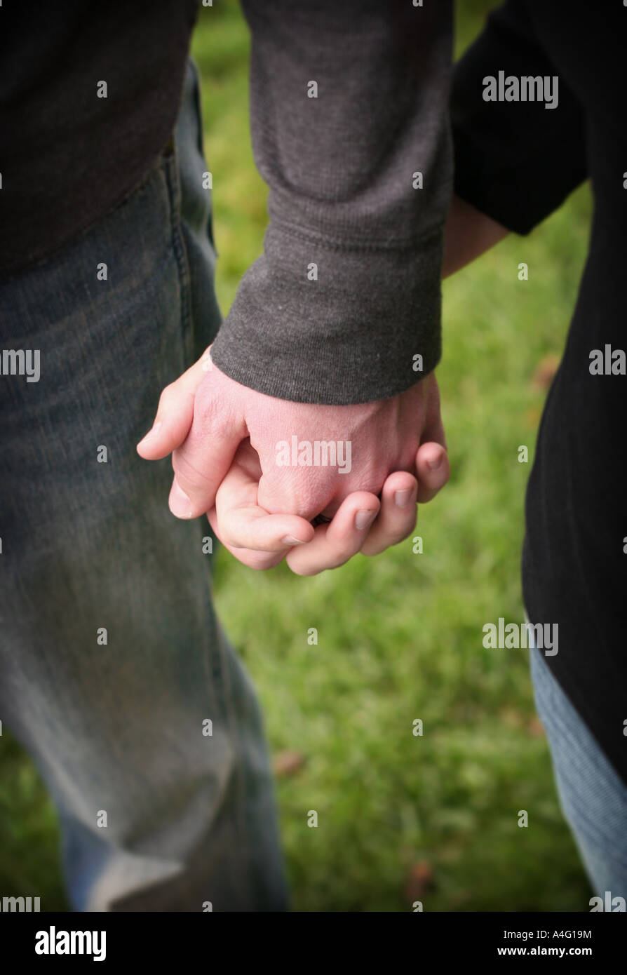 Couple holding hands wearing jeans in the green grass Stock Photo - Alamy