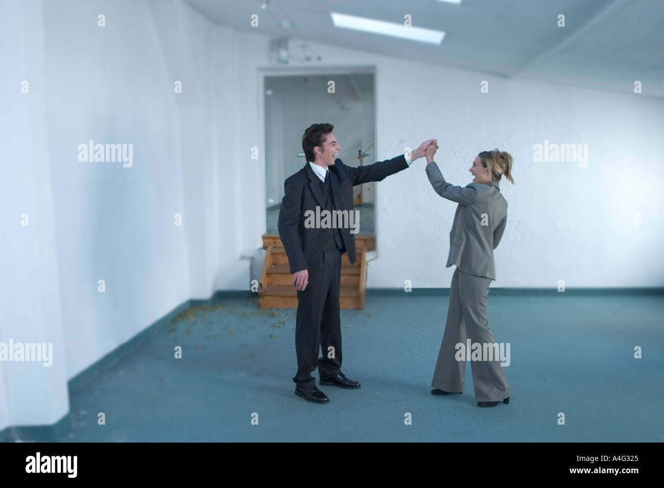 MR Man and woman in business dress cheer in an empty loft Stock Photo