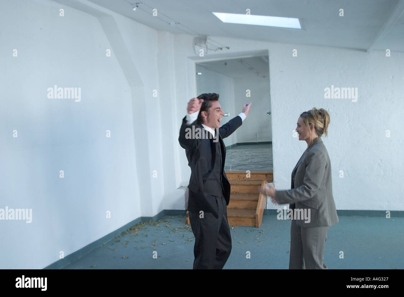 MR Man and woman in business dress cheer in an empty loft Stock Photo
