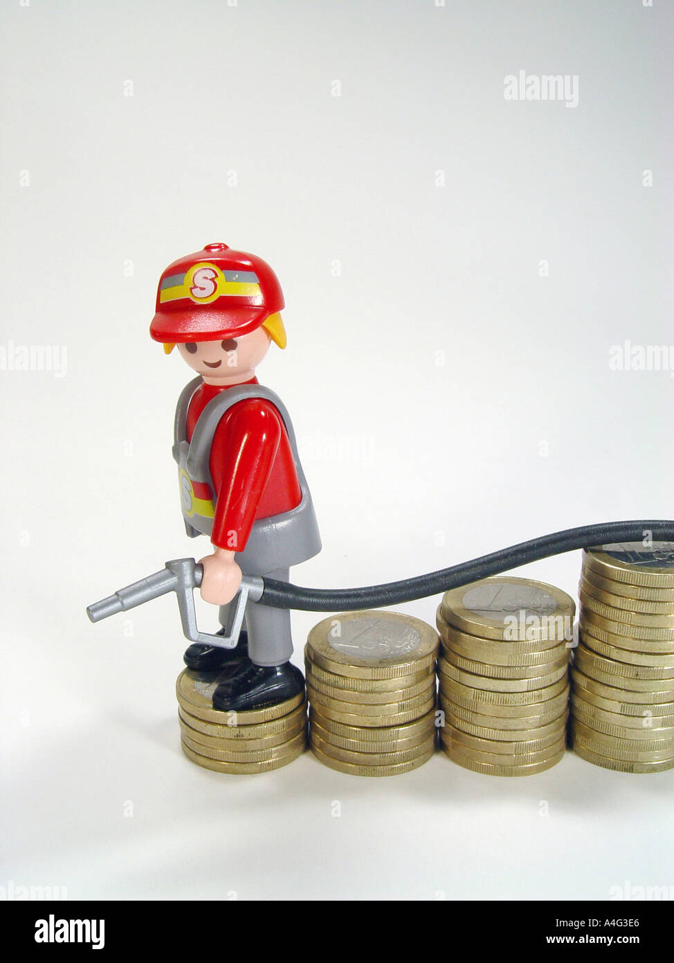 Service station attendant on a pile euro coins as symbol for the sinking fuel prices Stock Photo