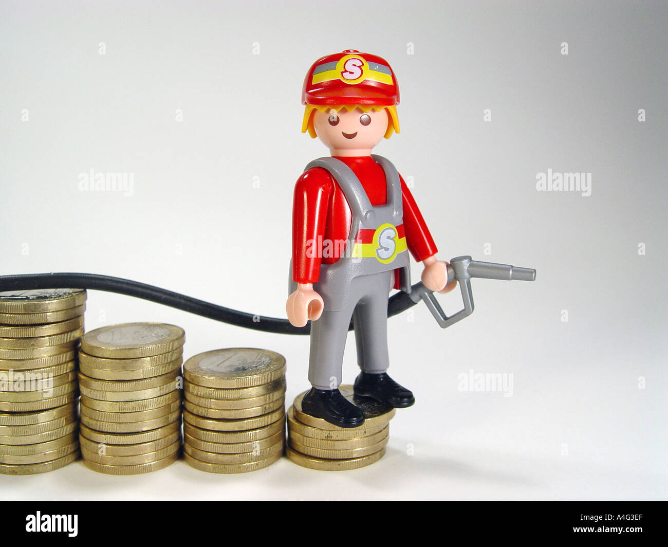 Service station attendant on a pile euro coins as symbol for the sinking fuel prices Stock Photo