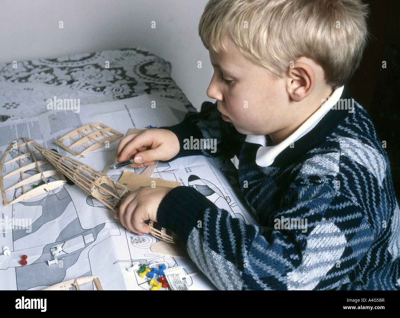 Young boy working on balsa wood flying model of classic Spitfire fighter aircraft. Stock Photo