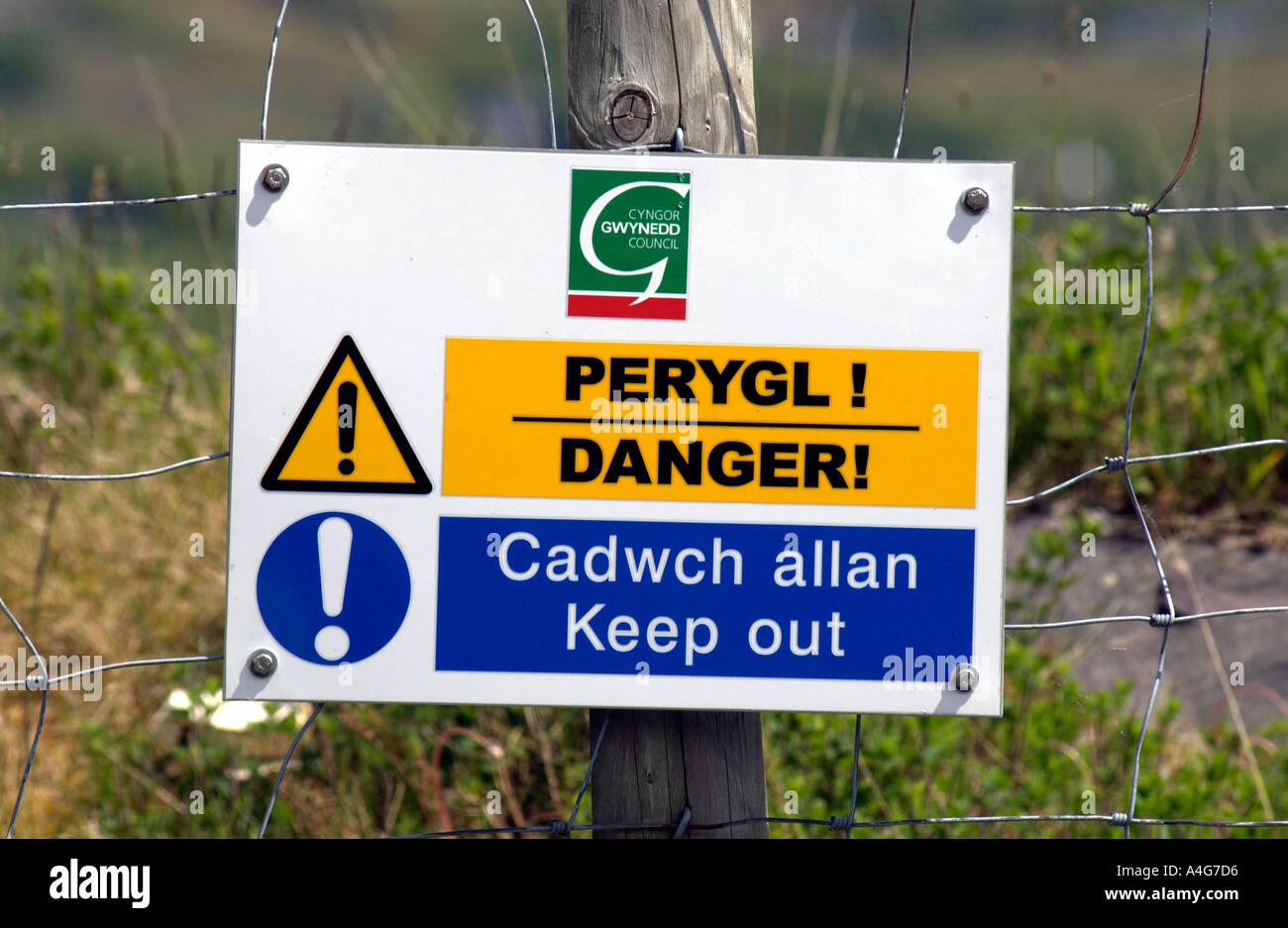 DANGER KEEP OUT bilingual Welsh English language sign on FENCE in Snowdonia Gwynedd Wales UK Stock Photo