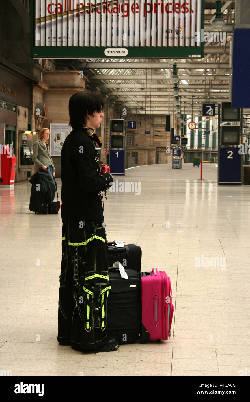 Boy man passenger waiting at Glasgow train station with luggage Stock
