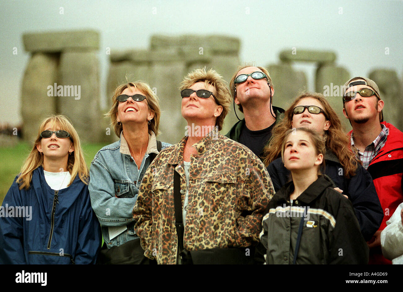 A GROUP OF TOURISTS FROM THE USA WATCH THE SOLAR ECLIPSE AS IT CASTS ITS SHADOW OVER STONEHENGE WILTSHIRE UK Stock Photo