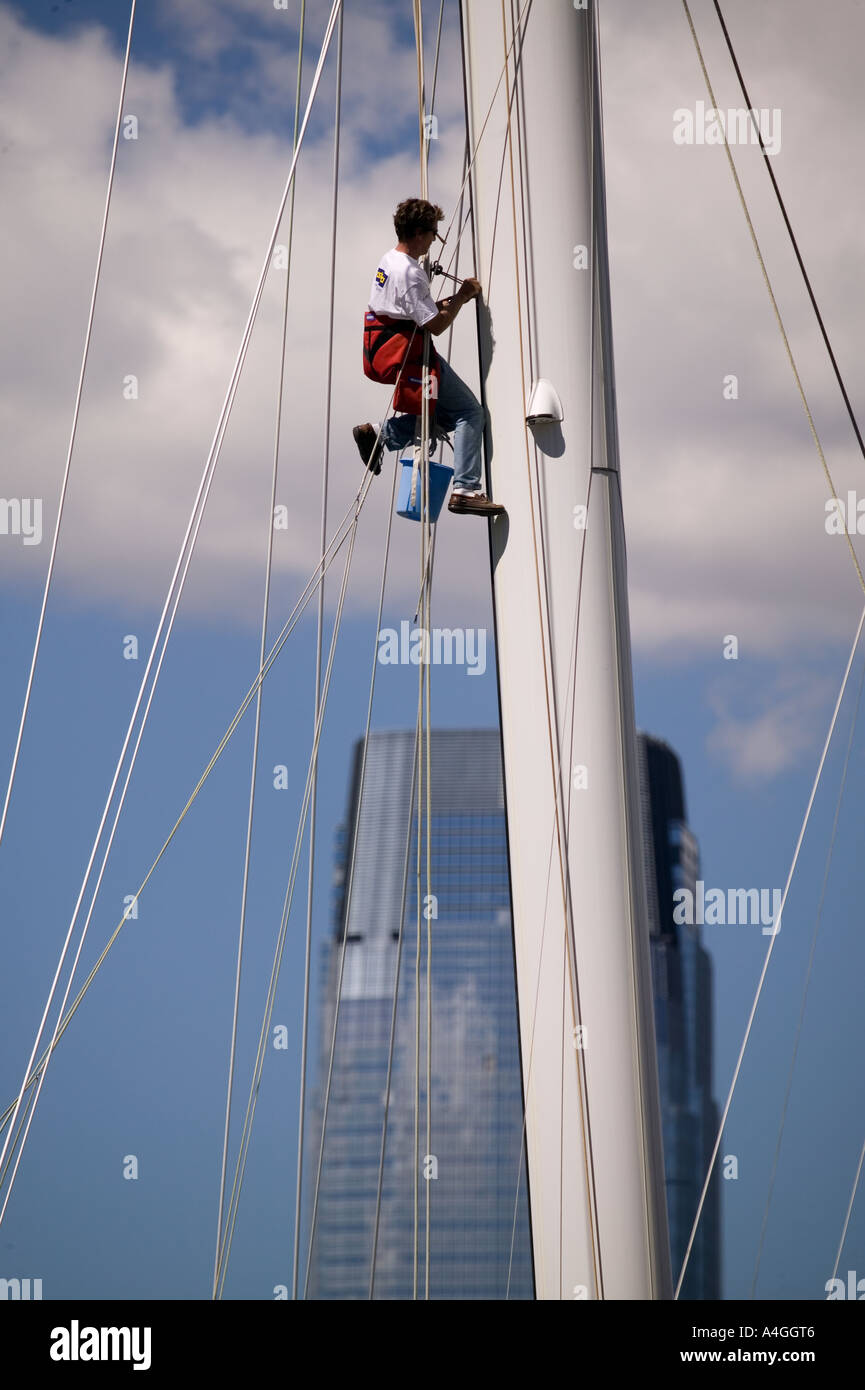A navigator climbs the mast of a sport sailing boat in a harbor in New York City USA 2005 Stock Photo