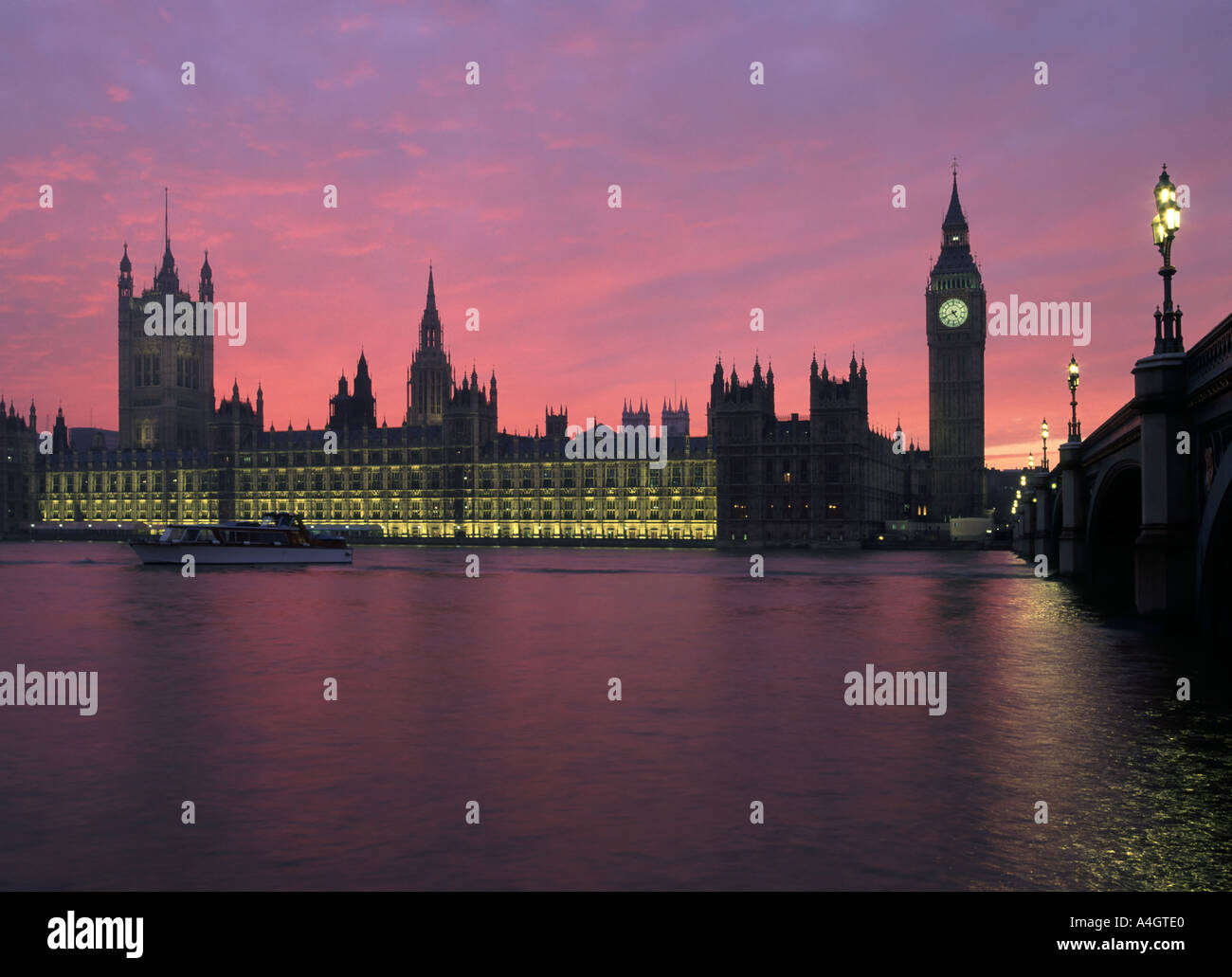 Houses of Parliament Big Ben Westminster Bridge and River Thames at sunset with commons sitting lamp on big ben Stock Photo