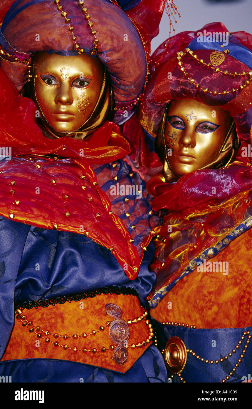 Two people dressed in bright red and blue lavish costumes and gold ...