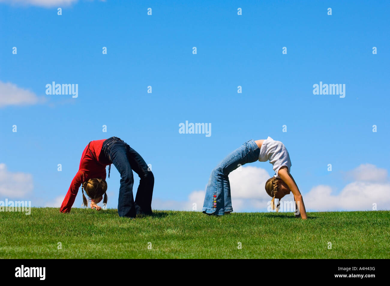 Two girls doing back arches on the grass Stock Photo