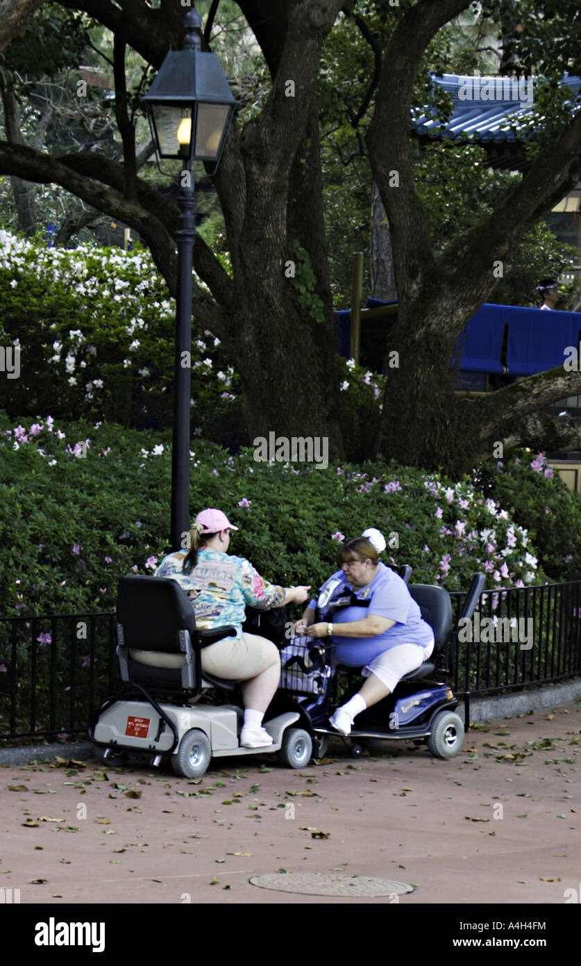 FLORIDA ORLANDO Morbidly obese mother and daughter in electric scooters share a funnel cake in the park Stock Photo