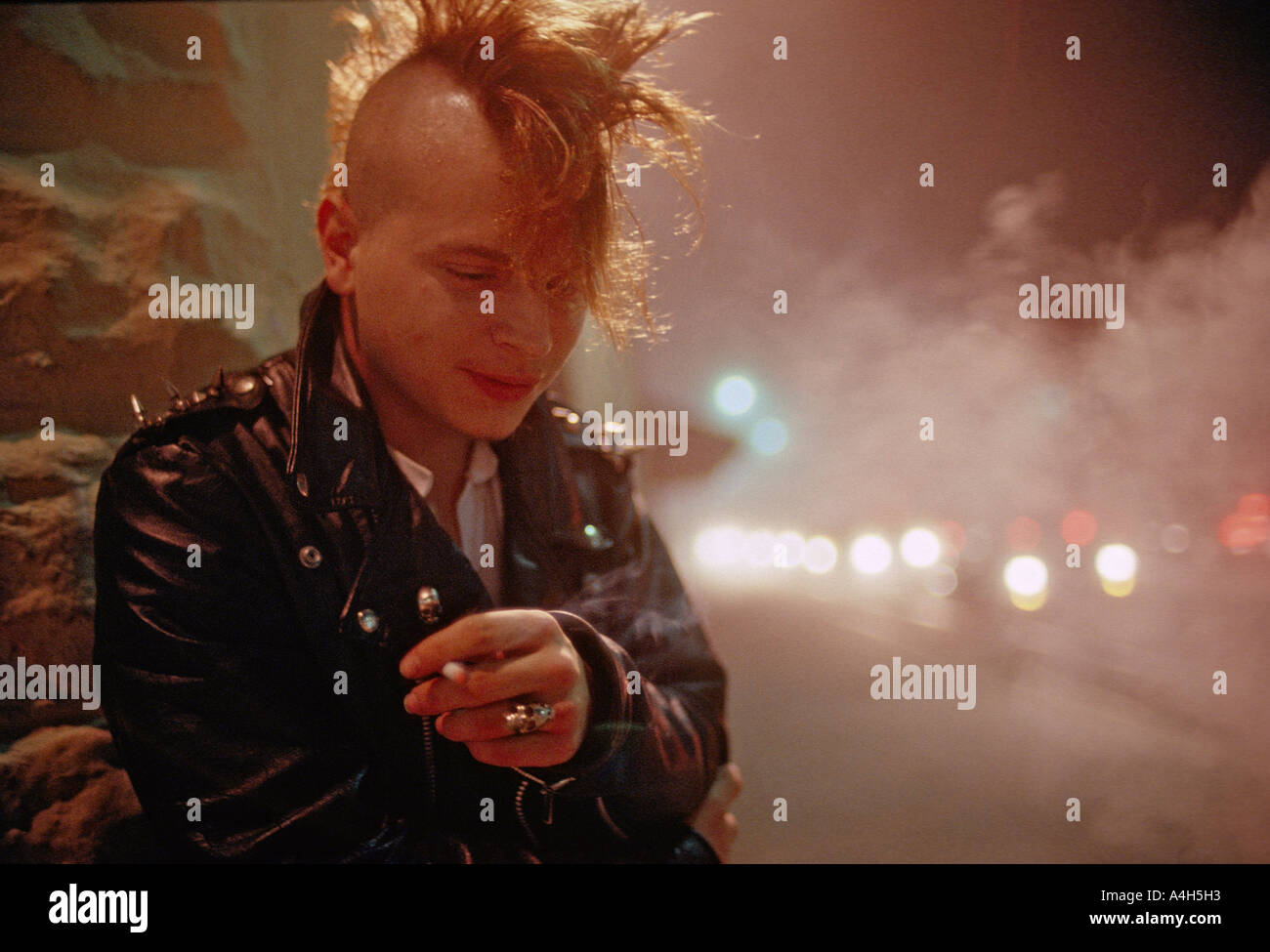 Young man with mohawk haircut smokes a cigarette outside an alternative nightclub club in Jacksonville Florida USA Stock Photo