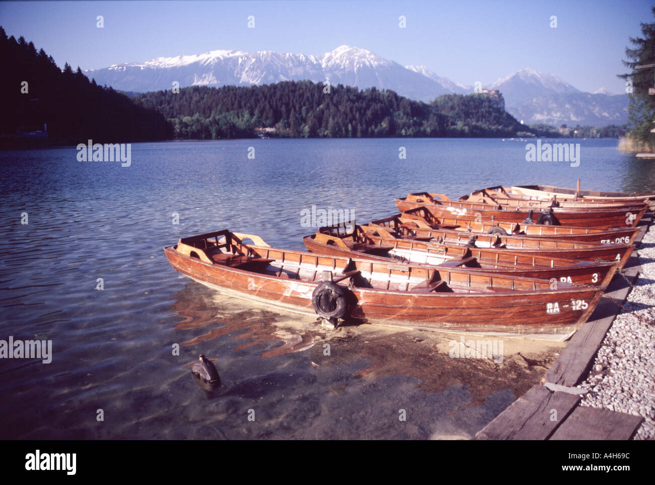 Rowingboats on lake Bled at sunset with mountains and castle in the ...