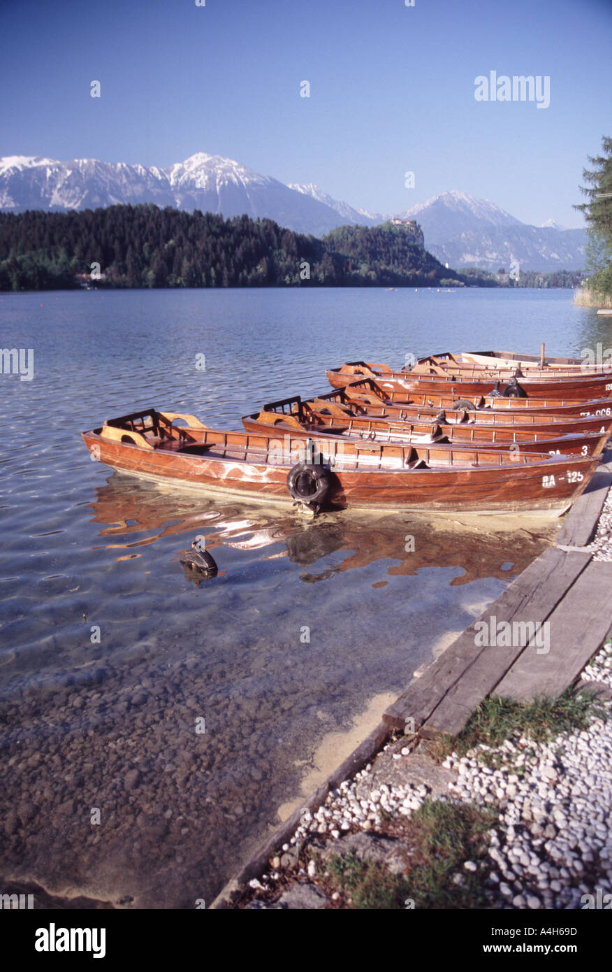 Rowingboats on lake Bled at sunset with mountains and castle in the ...