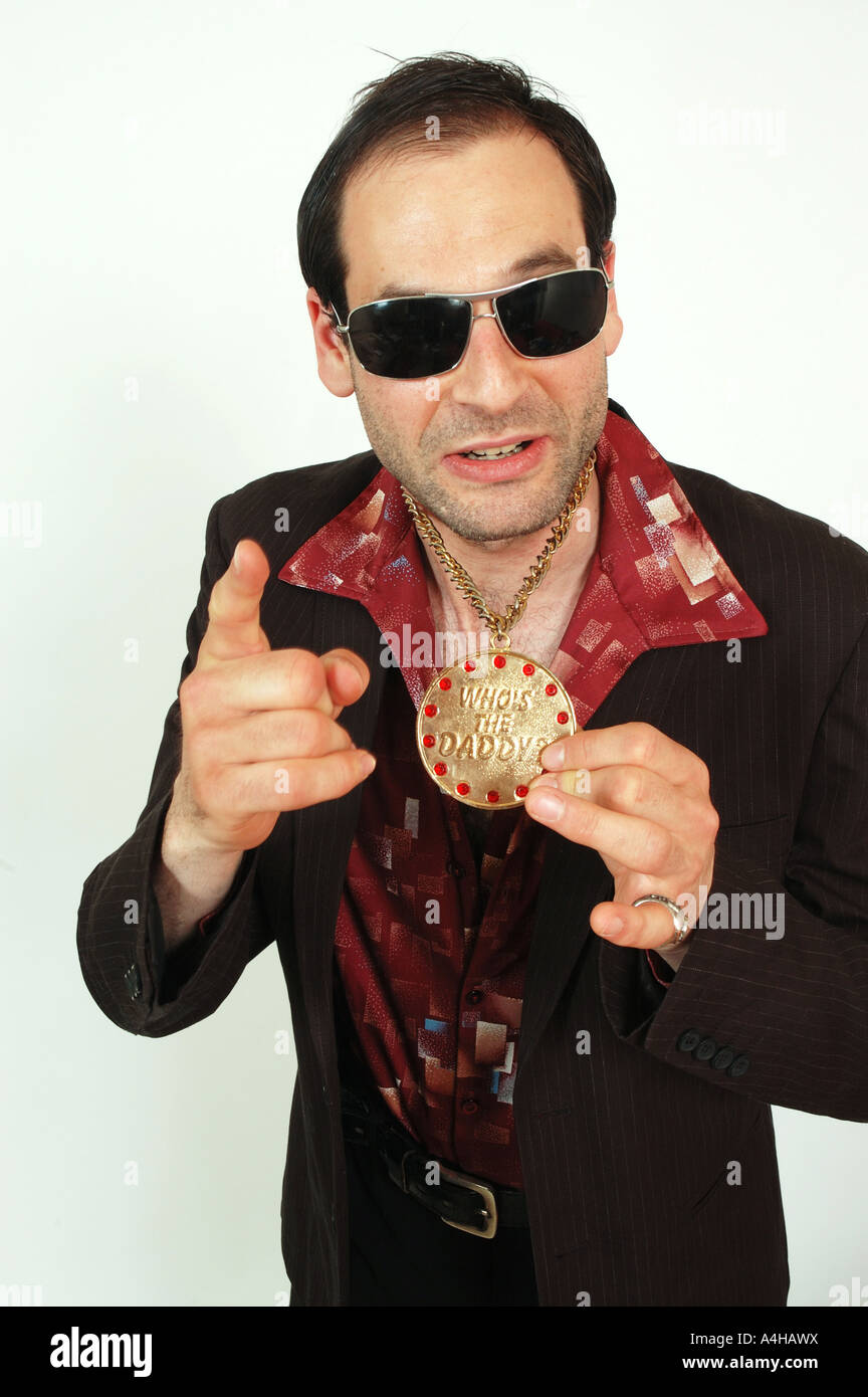 A sleazy looking man holding a medalion pointing to camera Stock
