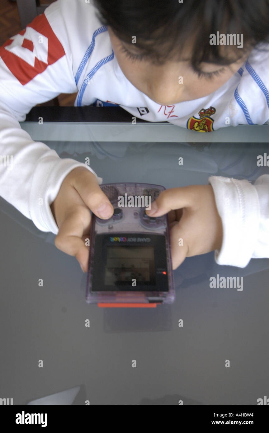 Eight year old Spanish young boy playing pokemon s game with a gameboy color  machine dressed with Real Zaragoza s soccer team un Stock Photo - Alamy